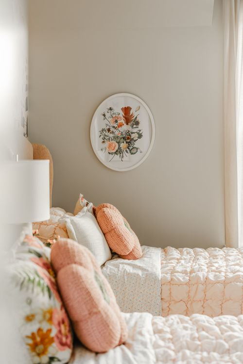 Bedside detail with round floral wall art and peach knit throw pillows