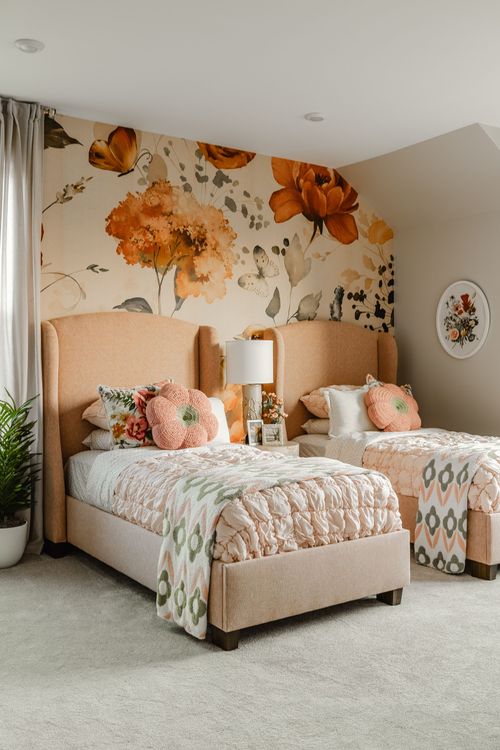 Twin bedroom with peach wingback headboards beneath a large-scale floral wallpaper mural