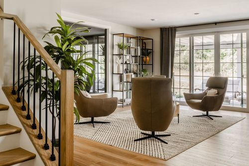 Lower-level lounge with swivel leather chairs, a ladder bookshelf and glass patio doors