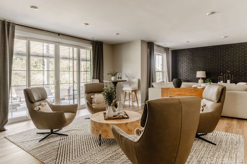 Lower-level lounge with leather swivel chairs, a round wood coffee table and black accent wall