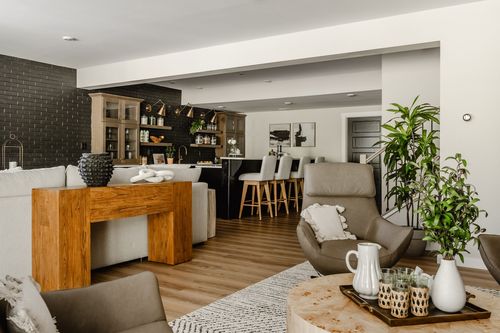 Basement family room with a live-edge console table, gray sectional and black brick accent wall