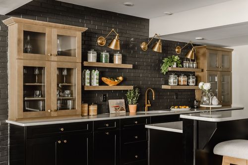 Basement bar with light wood glass-front cabinets, black brick wall and open shelving