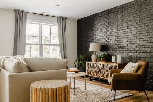 Living room with a black brick accent wall, woven-front console and leather chair