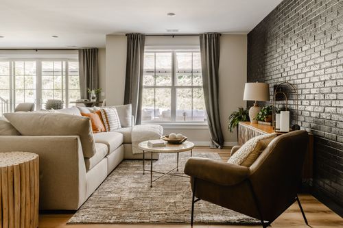 Living room with a beige sectional, black brick accent wall and leather armchair