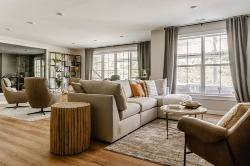 Lounge with a beige sectional, swivel accent chairs and a black brick fireplace wall