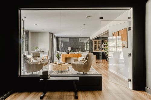 Glass-walled sunroom looking into a living room with a black brick wall and wood console