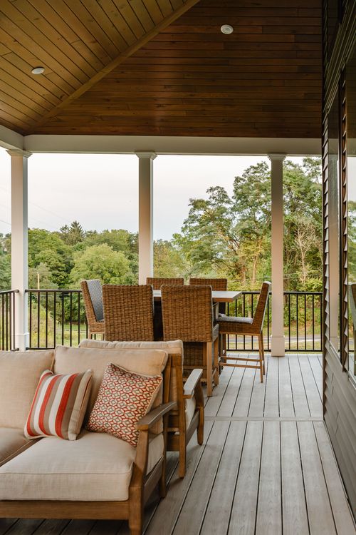 Covered porch with a wood-paneled vaulted ceiling, wicker dining set, and cushioned bench seating