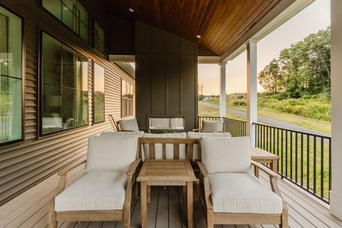 Covered porch lounge seating with wood-framed cushioned chairs and an ottoman