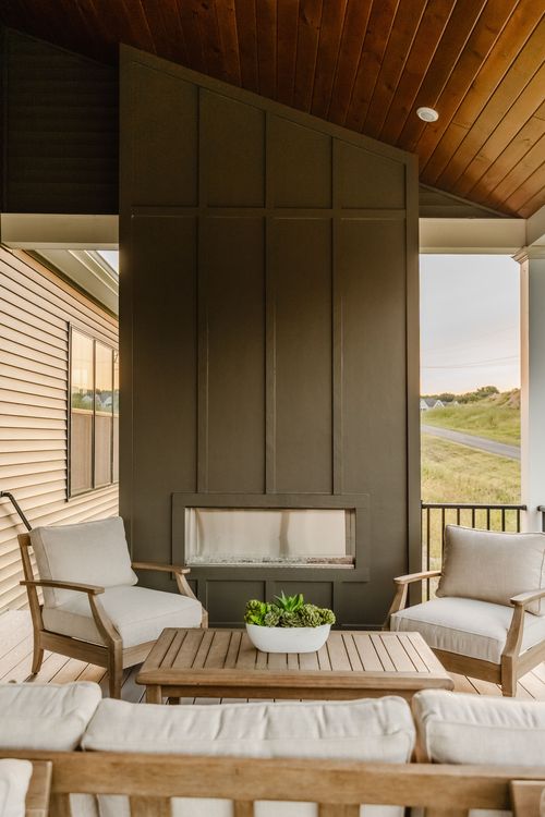 Covered patio with a modern linear fireplace set into a dark board-and-batten wall