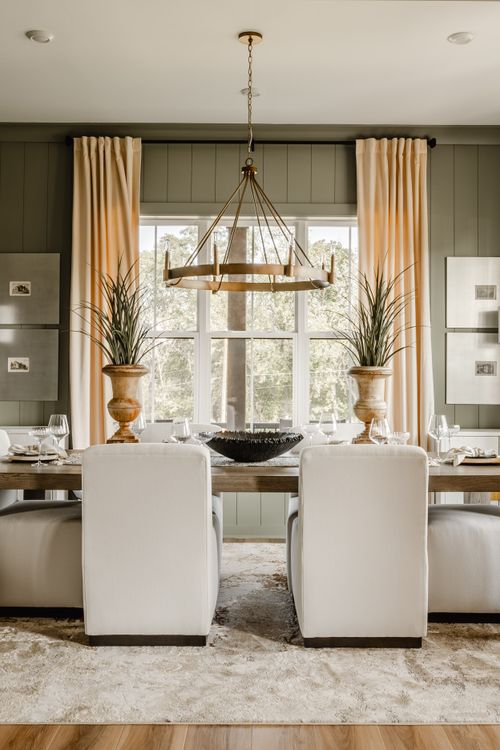 Dining room with a brass wagon-wheel chandelier, sage walls, and floor-to-ceiling curtains