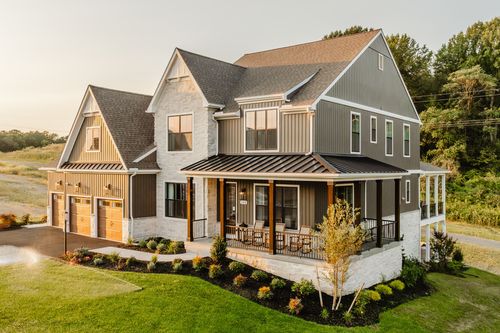 Aerial view of a two-story farmhouse with a wraparound porch and metal-roofed entry