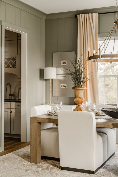 Dining table set with wine glasses beside a butler's pantry pass-through