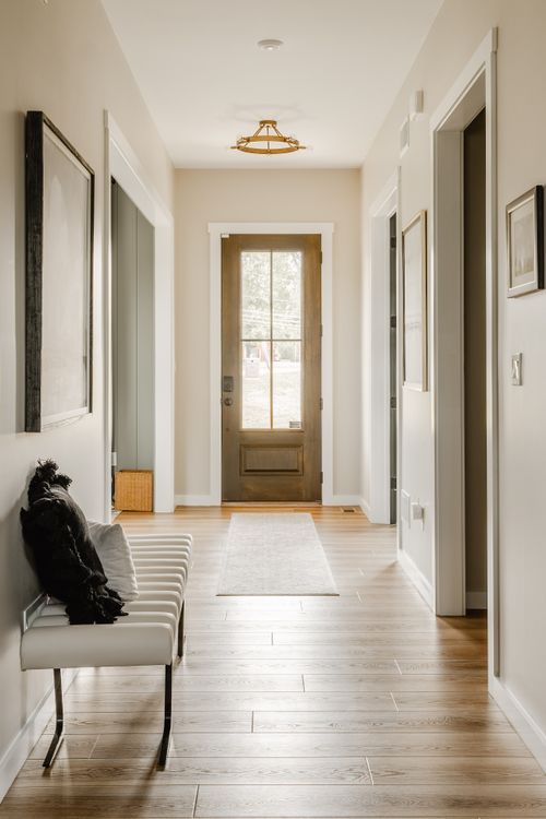 Entry hallway with a wood front door, upholstered bench, and wide-plank flooring