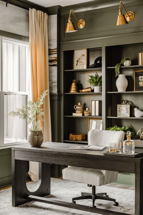 Home office with sage curtains, a dark wood desk, and styled built-in bookshelves