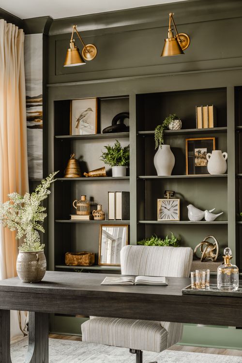 Home office bookshelf detail with brass sconces, ceramic vases, and framed art