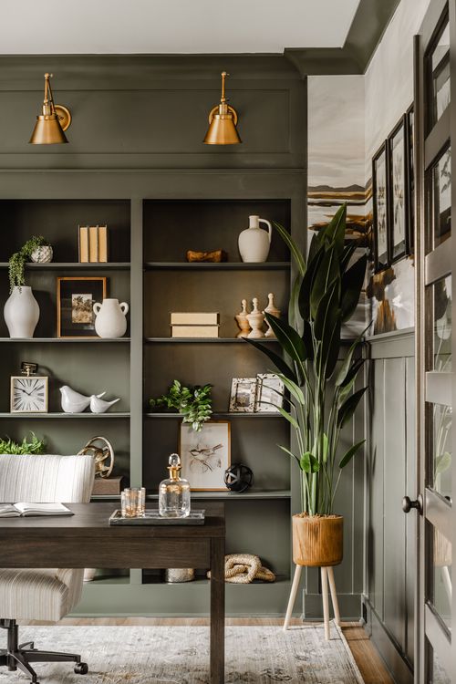 Home office bookshelf styling with brass sconces, ceramic vases, and a potted plant