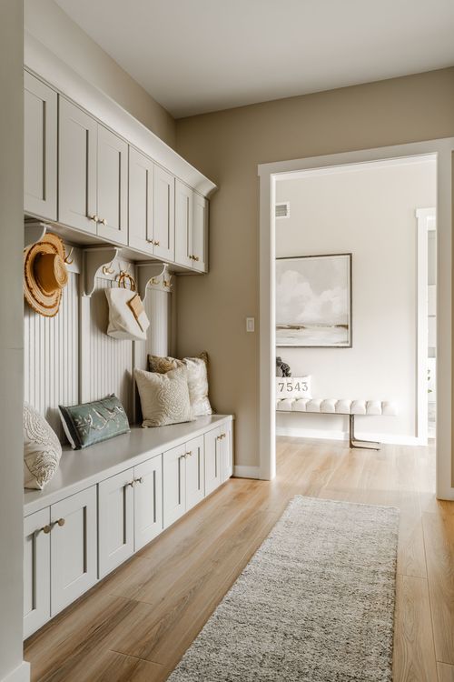 Mudroom with white built-in cabinetry, a cushioned bench, and a view to the foyer