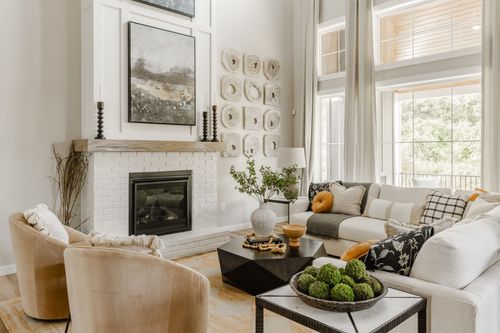 Living room with a white brick fireplace, layered wall art, and a sectional sofa