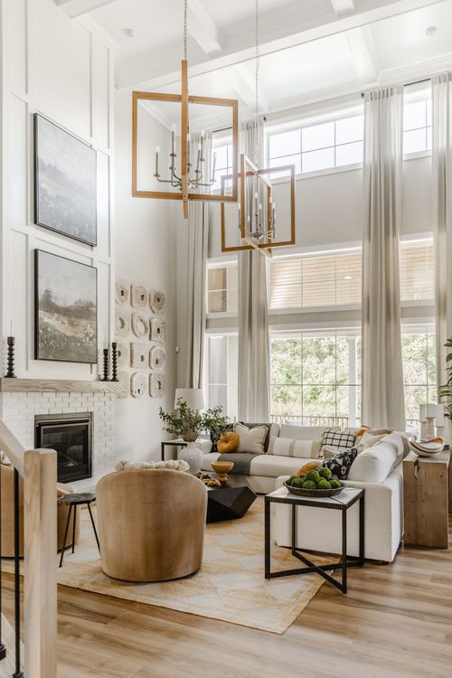 Two-story great room with oversized wood-framed chandeliers and a white brick fireplace