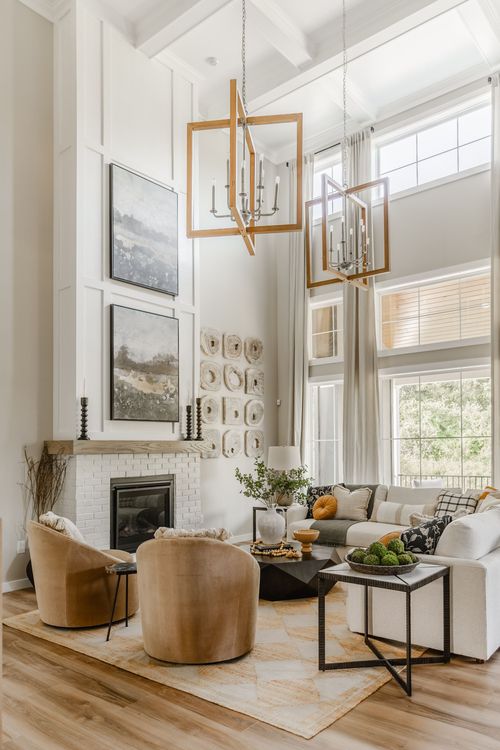 Great room with dual geometric wood chandeliers, tall windows, and a sectional sofa