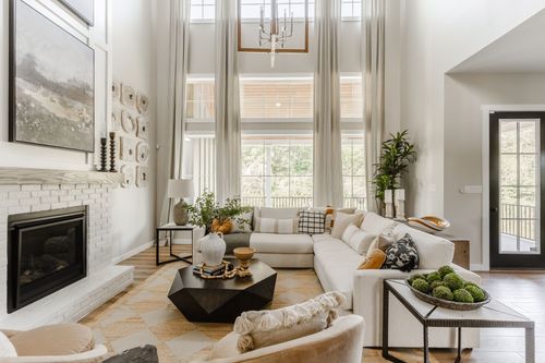 Two-story living room with a white brick fireplace, sectional sofa, and floor-to-ceiling windows