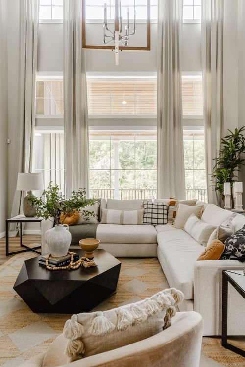 Living room sectional beneath a wagon-wheel chandelier and a two-story window wall