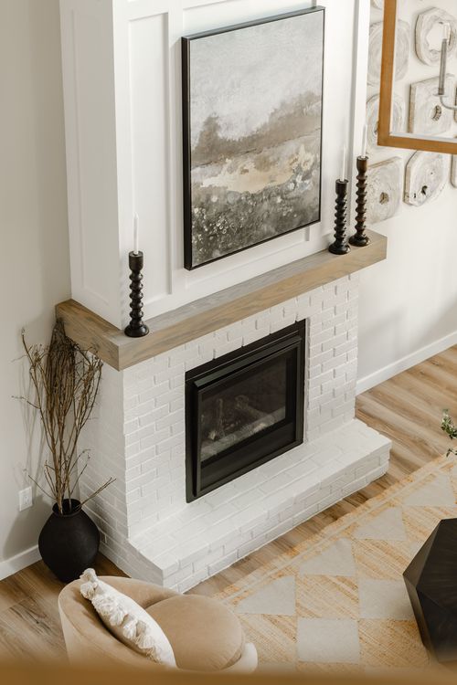 White brick fireplace detail with abstract art, taper candles, and a textured accent wall