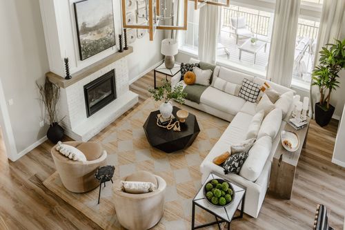 Aerial view of a two-story living room with a white brick fireplace and sectional sofa