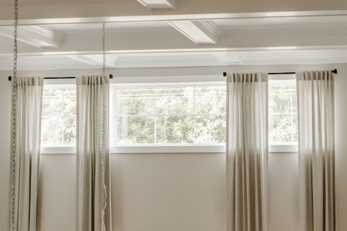 Coffered ceiling detail above tall windows dressed with striped curtains