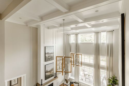 Coffered ceiling with a two-story window wall above a wood-framed chandelier