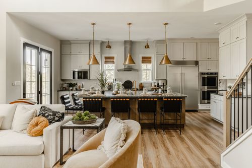 Open-concept kitchen with an island seating four beneath brass pendant lights