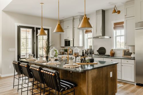 Kitchen island with brass pendant lighting, black French doors, and leather bar stools