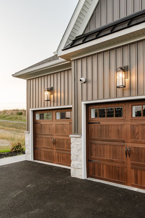 Close-up of wood-tone garage doors flanked by stone accents and wall sconces