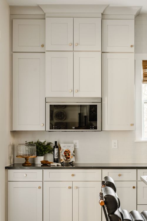 Built-in microwave nook flanked by white cabinetry and black countertops