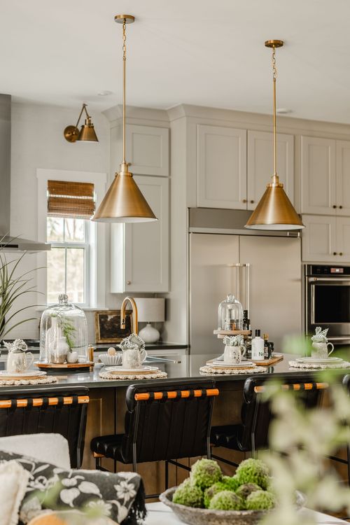 Kitchen island with matching brass pendants, black countertop and stainless refrigerator