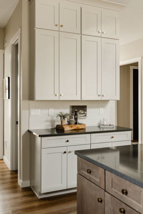 Kitchen counter nook with cream cabinetry, black countertop and small framed artwork