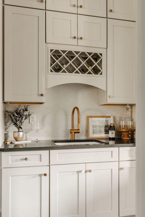 Butler's pantry sink with a brass gooseneck faucet and marble tile backsplash