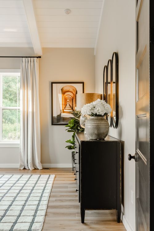 Entryway with a black console table, layered round mirrors, flowers and shiplap ceiling