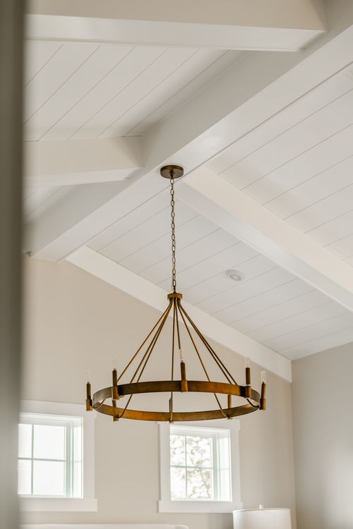 Vaulted shiplap ceiling with a wagon-wheel chandelier and paired dormer windows