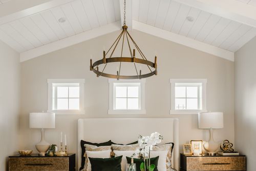 Symmetrical primary bedroom nightstands with lamps, candlesticks and a wagon-wheel chandelier