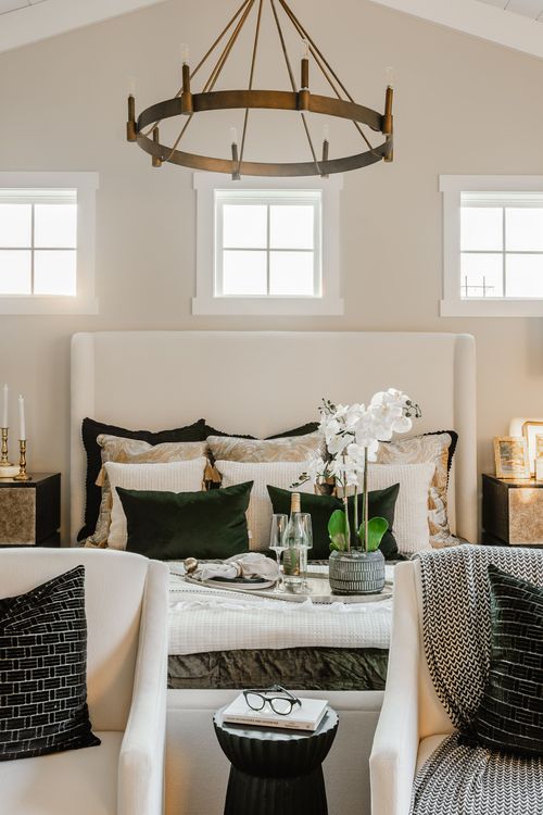 Bed styled with green velvet pillows, an orchid and a bottle chilling on a tray