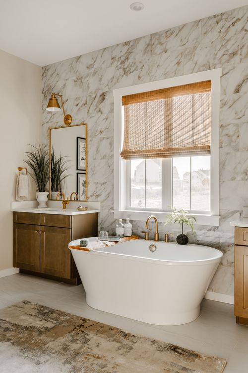 Bathroom with marble tile, a freestanding tub and a bamboo roman shade over the window