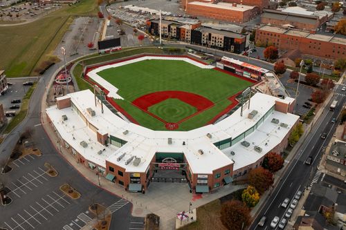 Aerial view of a baseball stadium's red dirt infield and green outfield surrounded by rowhomes