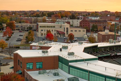 Aerial view of a stadium's rooftop and HVAC units above a downtown street at dusk