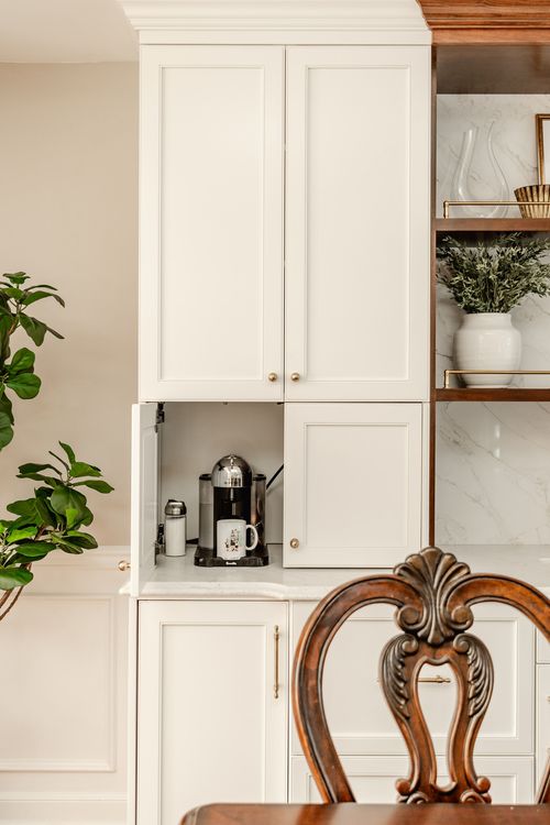 Hidden coffee station tucked behind cabinet doors with an espresso machine and mug