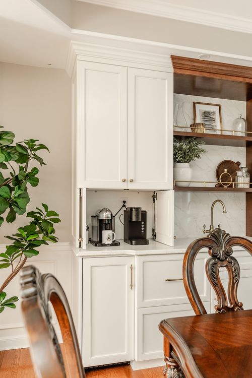 Built-in coffee bar with cabinet doors open revealing an espresso machine beside a wood hutch