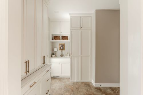 Mudroom hallway with floor-to-ceiling cabinetry, woven baskets and tumbled tile flooring