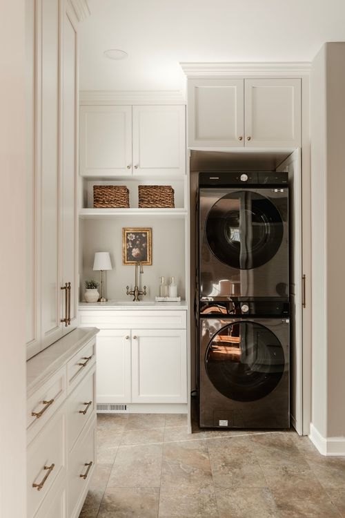Laundry closet with a stacked black stainless washer and dryer behind cabinet-front doors