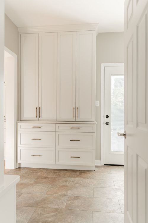 Hallway with a tall white built-in dresser and brass drawer pulls leading to a glass-paned door