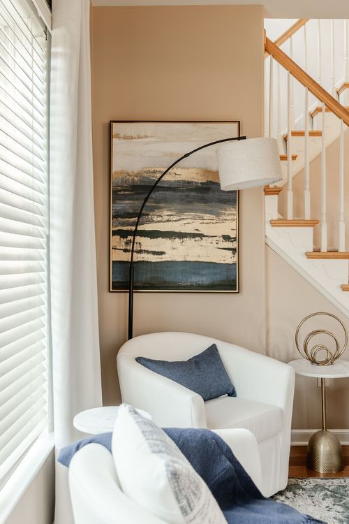Sitting corner with an abstract painting, arc floor lamp and a white swivel chair